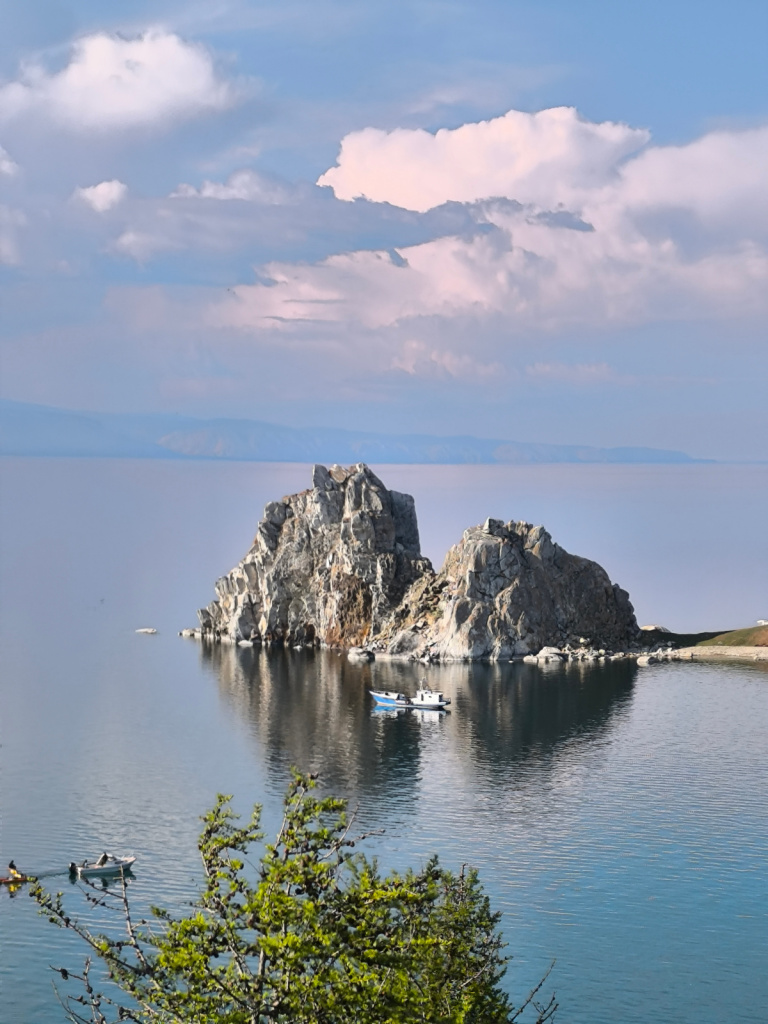 Скала Шаманка на мысе Бурхан на Байкале летом, рядом кораблик на воде. 